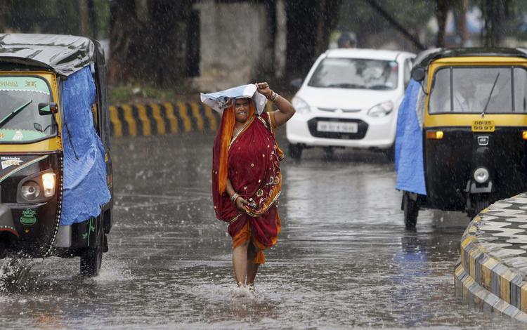 UVEJR. Cyklonen Hudhud sendte i oktober enorme vandmængder ned over indiske kyststrækninger. Her vader en kvinde gennem en  oversvømmet gade i Bhubaneswar i Indien. 