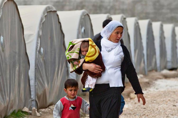 Alene. En syrisk-kurdisk kvinde, der er flygtet fra det terrorhærgede Kobani, går med sine børn. Det er tidlig morgen i en flygtningelejr i den tyrkiske by Suruc. 