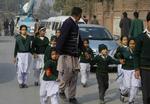 Internationalt. En sikkerhedsofficer fører børn, som er blevet reddet ud af den angrebne skole i Peshawar, væk fra området. 