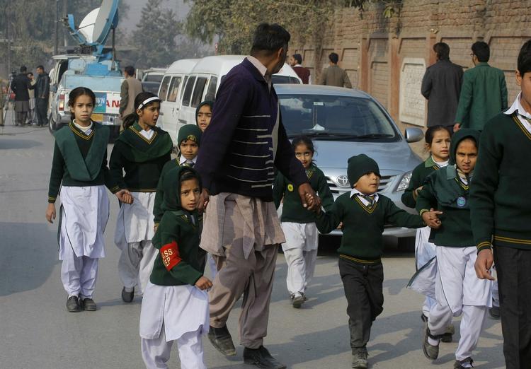 Internationalt. En sikkerhedsofficer fører børn, som er blevet reddet ud af den angrebne skole i Peshawar, væk fra området. 