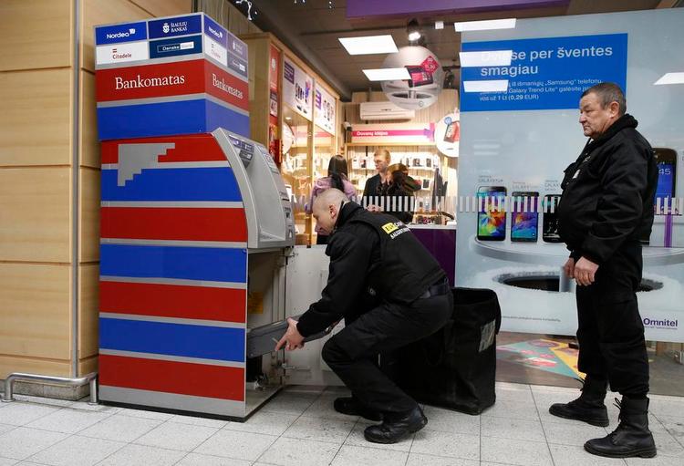milepæl. Bankfolk fylder en pengeautomat med euro forud for Litauens medlemskab af den fælles valuta, der træder i kraft i dag. 