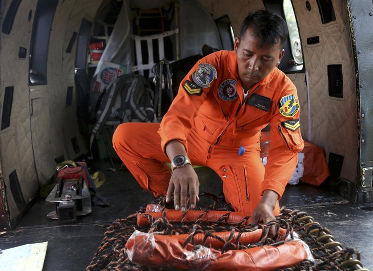 Et besætningsmedlem på en redningshelikopter er ved at klargøre udstyret, der bruges når dykkerne hejses ned i området, hvor AirAsia-flyet styrtede. Redningsarbejdet bliver vanskeliggjort af kraftig vind og høje bølger. 