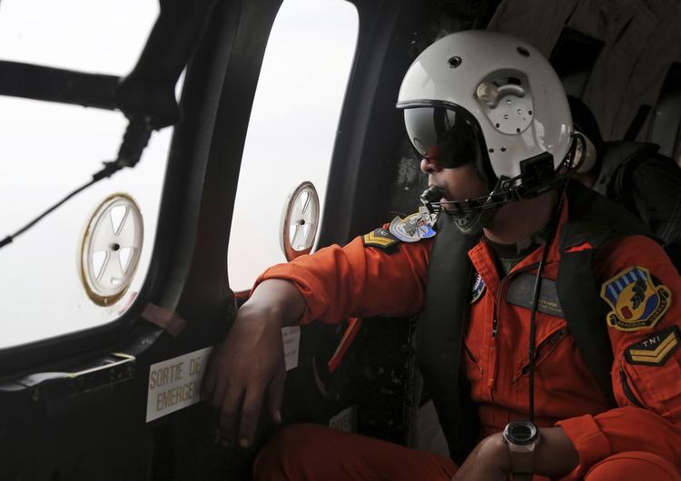 Redning. En pilot i en indonesisk militær-helikopter spejder efter vragdele og andre spor efter det forsvundne AirAsia-fly. 