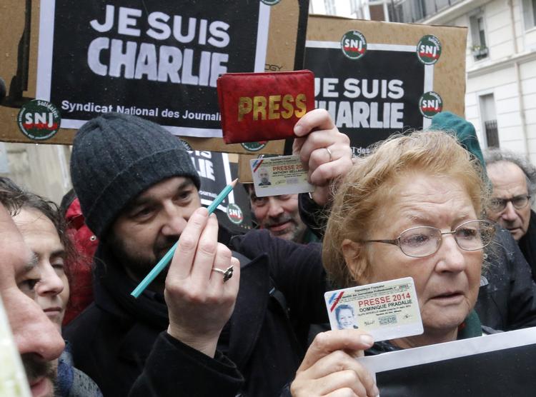 Sørgedag. Franske journalister markerer den nationale sørgedag ved at samle sig foran Charlie Hebdo. Her viser de deres pressekort og løfter blyanten op for at kæmpe for ytringsfriheden 