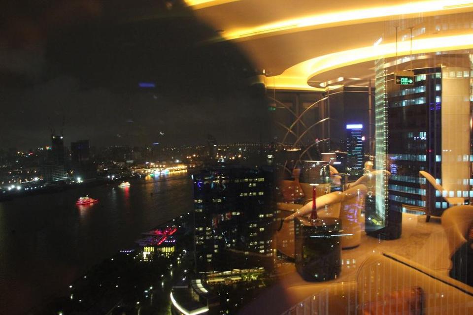 Shanghai. Billedet er af taget fra et hotel. Den ene halvdel er udsigten over floden om natten med de oplyste både på vandet, mens den anden halvdel er genskæret i vinduet fra hotelles lounge. FOTO: Rasmus Pedersen 