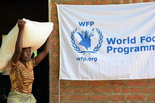 En kvinde bærer en sæk majsmel i en telt- og maddistributionslejr i byen Chikwawa i det sydlige Malawi. 