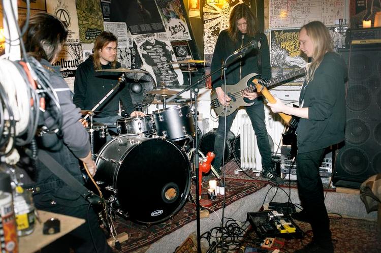 sort sol. Ungdomshuset på Dortheavej i Nordvest har været Solbruds base i mere end fem år, så de har haft god tid til at indrette deres øvelokale, der er tapetseret fra gulv til loft med plakater, flyers og klistermærker. Øverst til højre ses et whiteboard, hvor en gennemgang af to af bandets nye sange står nedfældet i et system, der er så sindrigt, at det indimellem kan være svært for bandet selv at holde styr på, hvem der skal spille hvad. 
