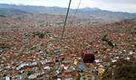 Højt. Den røde svævebane går fra El Alto 4.000 m.o.h. til La Paz' centrum 3.600 m.o.h. Turen er 2,4 km lang og tager 10 minutter. I baggrunden ses det sneklædte bjerg Illimani 6.442 meter højt og vartegn for La Paz. 