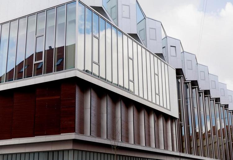 Veltilpasset. Huset er klart moderne, med meget store vinduesfelter på hjørnerne og i lejlighederne, men det er samtidig uden at være blevet det rene tilpasningsarkitektur virkelig godt tilpasset kvarteret. 