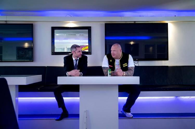 indenfor. Satudarahs advokat, Anders Schønnemann Olesen (t.v.), og medlemmet Kenneth glæder sig i klubhusets bar over afgørelsen fra byretten, som foreløbig udskyder Gladsaxe Kommune nedrivning af det røde klubhus, hvor andre medlemmer er trukket ud i solen. Foto: Finn Frandsen 