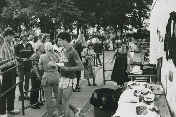 Dørene til stadion åbnede klokken 20, og der kom hurtigt pres på, da der kun var små bokse til at sluse folk igennem ind til deres pladser på betonrækkerne. Her ses en merchandisebod med t-shirts andre koncert-souvenirs. 