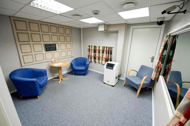 faste pladser. Anders Breivik sad til venstre, og i den anden stol til højre sad - på skift - de tre politifolk, der afhørte ham. Videnskabelige undersøgelser viser, at en samtale flyder lettere, når man sidder skråt for hinanden ved et lille bord, end når man sidder lige over for hinanden. I den tredje stol sad Behrings forsvarer, Geir Lippestad. 