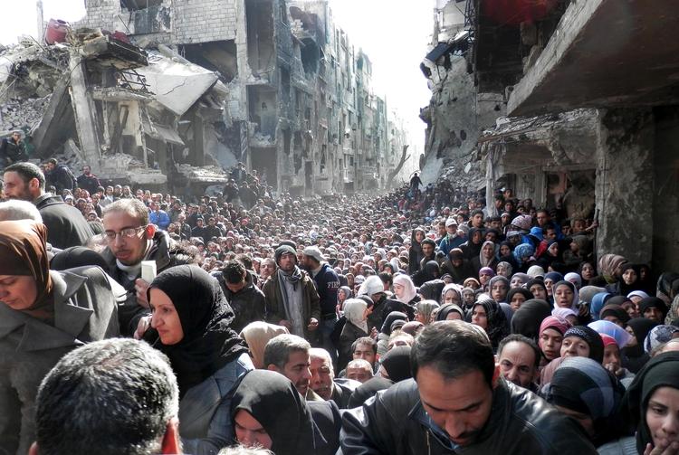 Nødhjælp. Flygtningelejren Yarmouk i udkanten af Syriens hovedstad Damaskus har været under belejring i flere år. På dette billede fra april sidste år står indbyggerne i kø efter mad. (arkivfoto) 