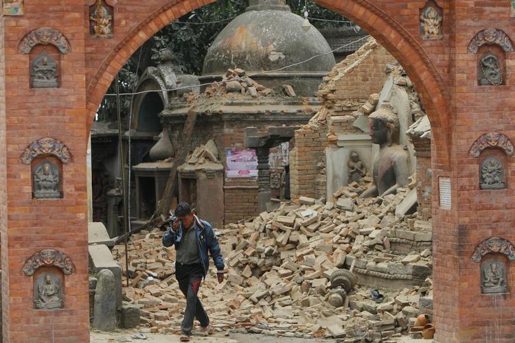 En mand græder, mens han går gennem murbrokkerne i Kathmandu. 