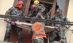 Redningsarbejdere trækker en overlevende i sikkerhed i et sammenstyrtet hus i Kathmandu. 