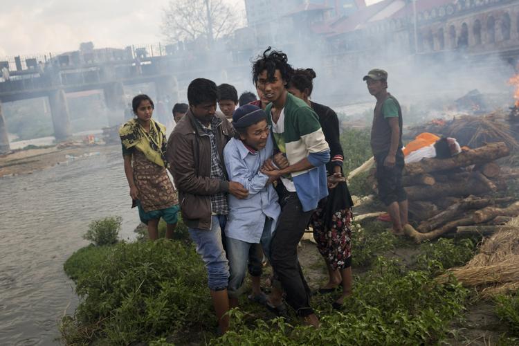 En mand er brudt sammen under en begravelse på bredden af Bagmati floden i Kathmandu. 