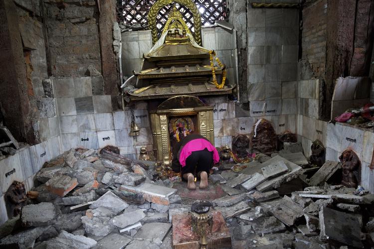 En kvinde beder i et ødelagt tempel i Kathmandu. 