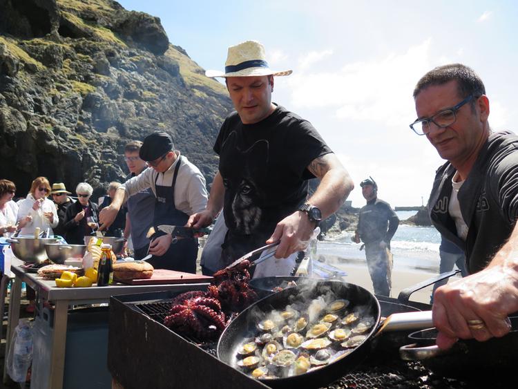 Havkøkken. Benoît Sinthon (i baggrunden) og Ljubomir Stanisic ( i midten) kokkerer de friskfangede havvarer over åben ild i det interimistiske køkken midt på en af de få sandstrande på Madeira. 