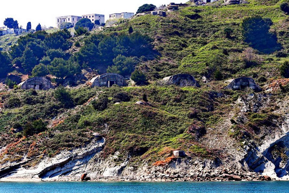 Historie. På Sazan Island kan man stadig se en villa, der i sin tid tilhørte den albanske forsvarsminister Beqir Balluku, der blev henrettet af diktator Enver Hoxha for forræderi i 1974. Diktatoren døde selv i 1985. 