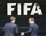 FIFA. To mænd taler foran forbundets logo ved hovedkvarteret i Schweiz. 