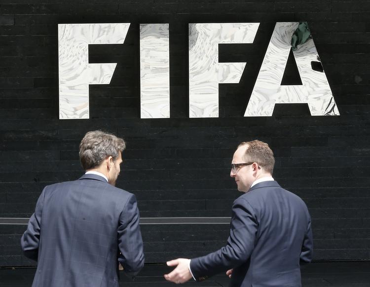 FIFA. To mænd taler foran forbundets logo ved hovedkvarteret i Schweiz. 