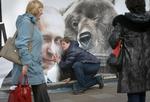 Lydhør? En forbipasserende kvinde pjatter ved en plakat med præsident Putin og en bjørn i Sankt Petersborg 1. maj i år. Foto: Dmitry Lovetsky/AP 
