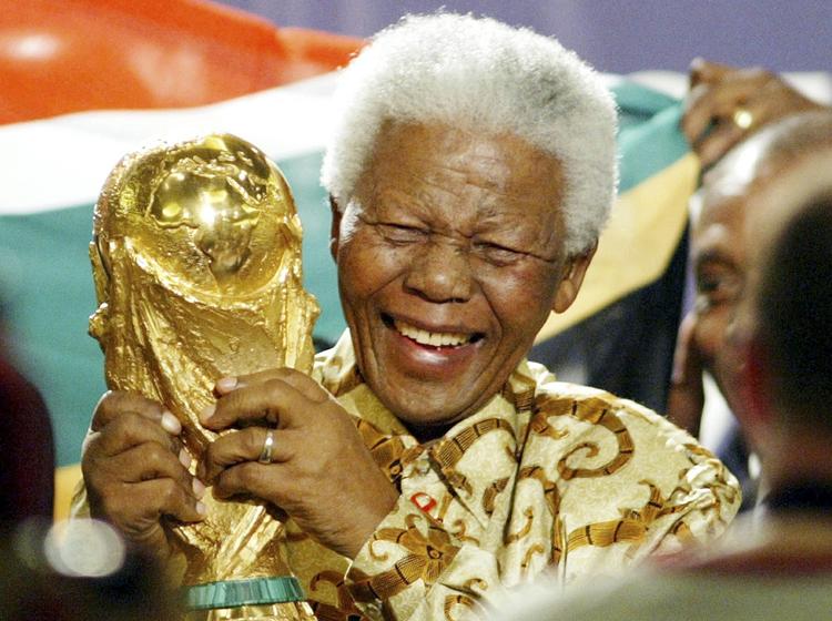 GLÆDE. Den nu afdøde præsident Nelson Mandela løfter glædesstrålende VM-trofæet, da han i 2004 i Zürich får at vide, at Sydafrika skal være vært for fodbold-VM. Nu skal landets bagmandspoliti undersøge, om der blev betalt bestikkelse til Fifa til gengæld for at få lov at afholde den store sportsbegivenhed. 