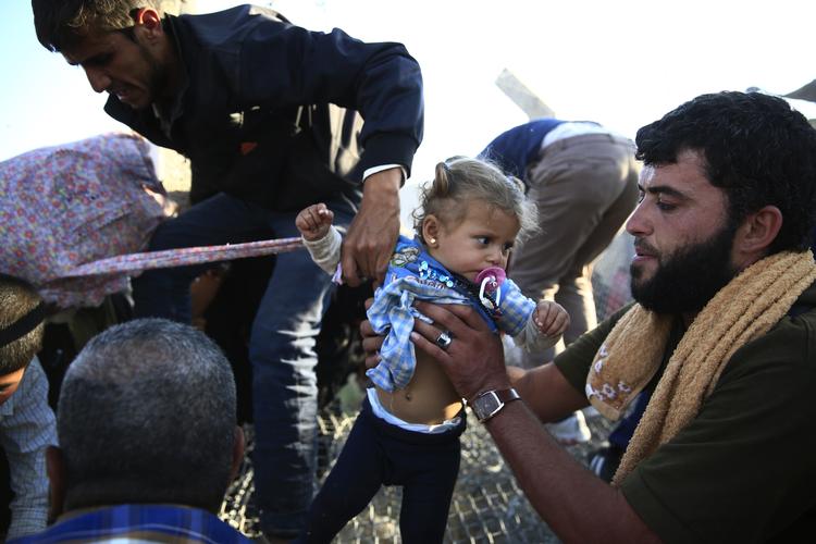 Beskyttelse. Verden har ikke siden anden verdenskrig set magen til flygtningestrøm som den nuværende. Her bliver en baby hjulpet over grænsen fra Syrien til Tyrkiet. 