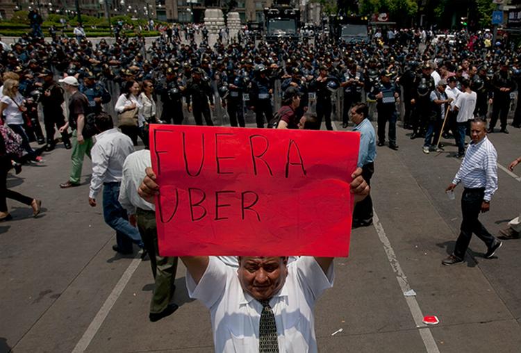 kontroversiel. Uber mødt med stærke reaktioner verden over, hvor de udfordrer den eksisterende taxa-branche med sin app, som tillader almindelige mennesker at tilbyde sig som chauffører. Her er vi i Mexico City i maj, hvor banneret forkynder 'Ud med Uber'. 