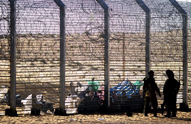 HEGN. Afrikanske migranter sidder på den egyptiske side af det hegn, Israel har opført langs de to landes fælles grænse. Nu kommer der et tilsvarende hegn mod naboen i øst, Jordan. 