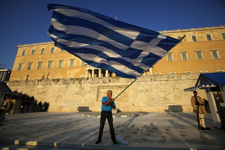 Gældskrise. En tilhænger af euroen vifter med et græsk flag foran det græske parlament i dag. Den græske regering havde indtil midnat til at aflevere et nyt forslag til reformer til euro.gruppen. 