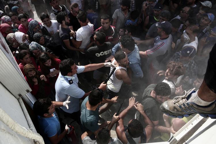 Grænser. En politimand slår en flygtning under uroligheder på Kos. Uroen opstod tirsdag blandt hundredvis af migranter, der ventede på at blive registreret på den græske ferieø. 