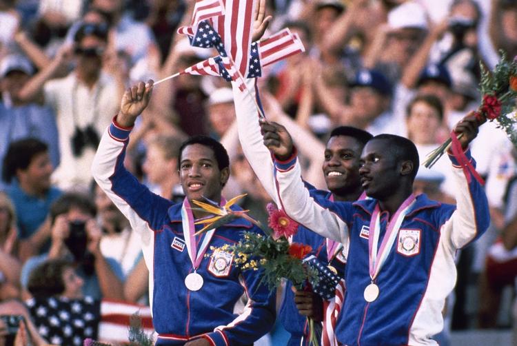 hjemmebane. Carl Lewis var et af de store navne ved OL i 1984 i Los Angeles. Her fejrer han sit guld på 200 meter foran landsmændene Kirk Baptiste (tv.) og Thomas Jefferson (th.). 