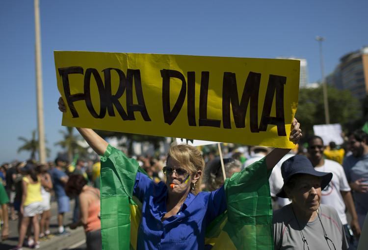 Skrid. Nationalfarverne blå,  gul og grøn dominerede, da tusindvis af brasilianere var på gaderne søndag i protest mod præsident Dilma Rousseff og hendes parti. 'Skrid, Dilma', står der på skiltet. Kun 7,7 pct. af befolkningen mener, at præsidenten gør et godt job. 