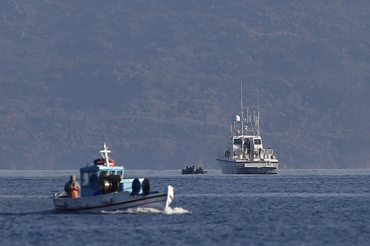 Migrantkrise. Den græske kystvagt gør klar til at redde en båd med migranter på vej til Grækenland fra Tyrkiet. I forgrunden er en græsk fisker på arbejde. Billedet er fra mandag og er taget ved den græske ø Kos. FOTO: AP 