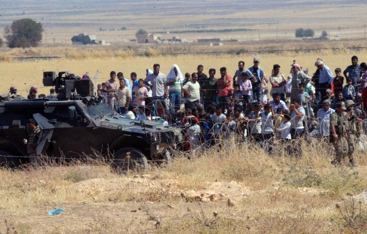 Lokalt. Flere flygtninge skal hjælpes i nærområderne. Her patruljerer tyrkiske soldater ved grænsen mellem Syrien og Tyrkiet, mens syriske flygninge venter på at krydse grænsen. 