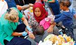Nødhjælp. En sygeplejerske fra Røde Kors hjælper en ung irakisk mor og hendes to børn med at blive registreret på hovedbanegården i München. Foto: Matthias Schrader/AP 