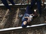 Internationalt. En kvindelig flygtning ligger tilbage på togsporet i byen Bicske med hendes spædbarn. Kort forinden er hendes mand blevet ført væk af bevæbnet politi, fordi familien blokerede togsporet. 