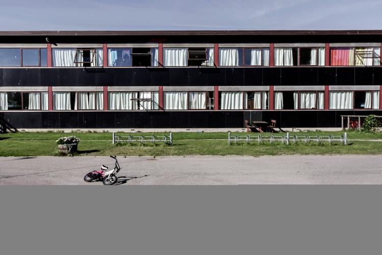 Asylcentrene er ikke en del af det danske samfund, men befinder sig på kanten af en velfærdsarkitektur fra vuggestuer over sygehuse til plejehjem, som vi bryster os af at være gode til. Vi anmelder tre centre indrettet i anlæg, der tidligere har tjent som henholdsvis kaserne, sanatorium og sindssygehospital. Her ses en del af Sandholmlejren. 