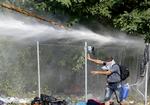 ANGREB. En flygtning kaster en trækævle mod Ungarns grænsehegn og politibetjentene på den anden side, der svarer med en vandkanon. 