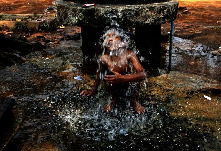 An Indian boy takes bath under a roadside public water supply tap on a hot afternoon in the eastern Indian city of Bhubaneswar, India, Friday, March 27, 2015. Heat wave conditions prevailed as temperature rises in costal parts of eastern India. (AP Photo/Biswaranjan Rout) 
