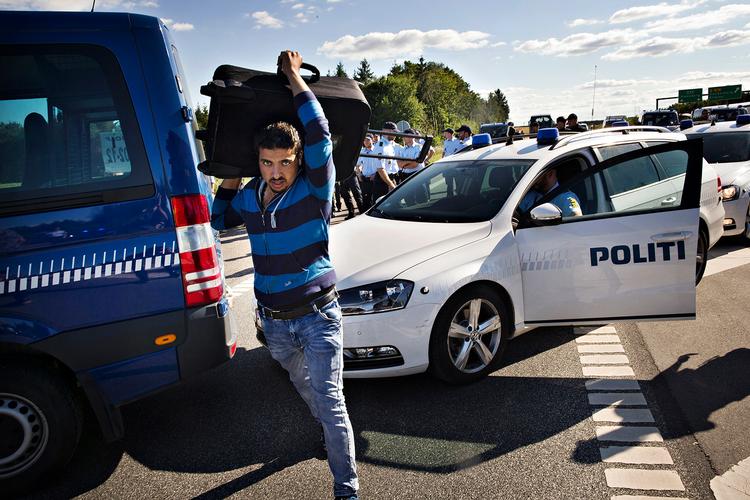 Politimænd danner kæde i den ene ende, deres vogne i den anden ende - men flygtningene smutter mellem bilerne og går videre. 