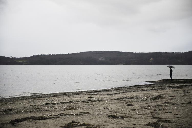 Udflytning. Mand paraply ved Vejle Fjord. Naturstyrelsen skal nu flytte til den smukt beliggende by. 