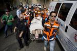 Såret. Israelsk ambulancepersonale bærer en såret person efter skyderier i Jerusalem i går. To israelere og en palæstinenser blev dræbt. 