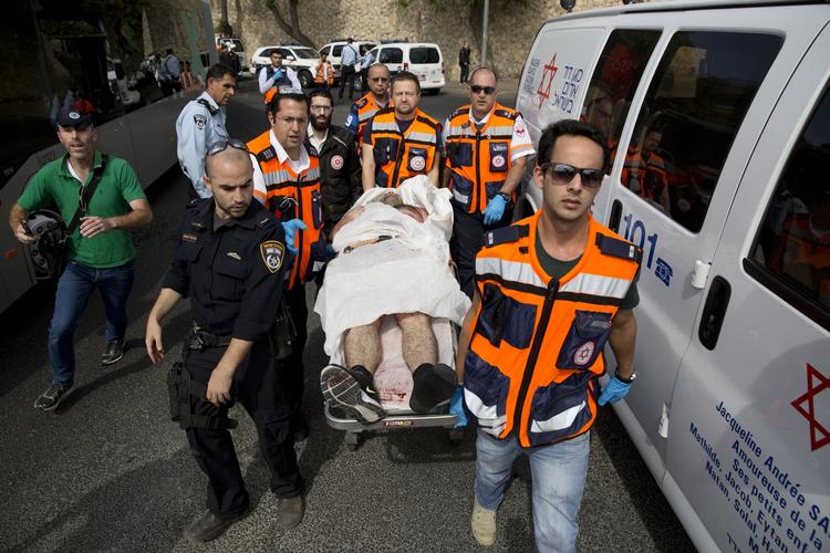 Såret. Israelsk ambulancepersonale bærer en såret person efter skyderier i Jerusalem i går. To israelere og en palæstinenser blev dræbt. 