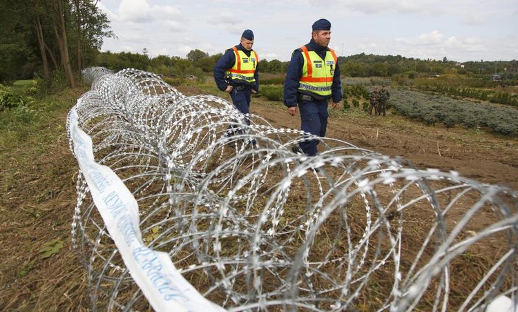 Spærret. To grænseofficerer går langs pigtrådshegnet, der deler Ungarn og Kroatien. 