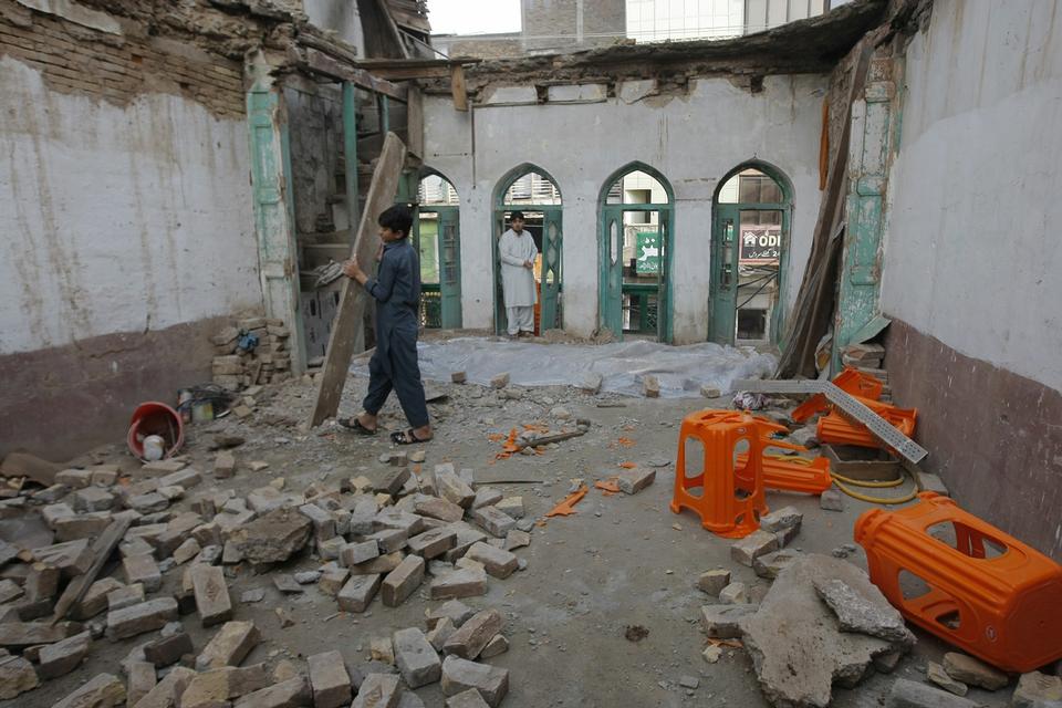 Denne dreng fjerner også inventar. Her er det et ødelagt huis i byen Peshawar i Pakistan. 