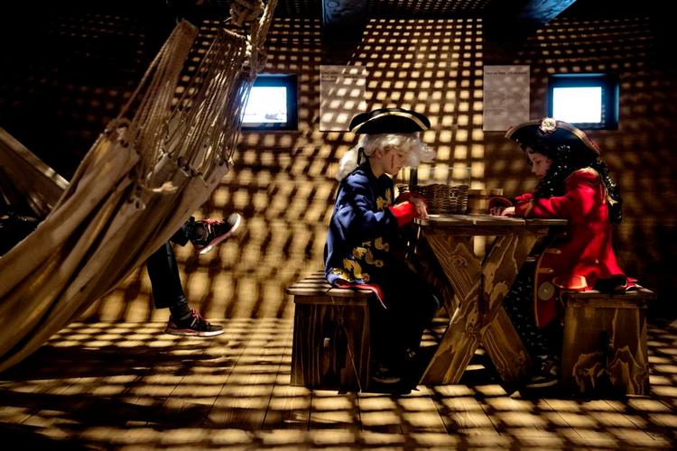 Under dækket sidder mia (tv.) og Lily, der besøgte Orlogsmuseet igår, sammen med Lilys mor Karen, som slapper af i en sømandshængekøje, mens pigerne iført Tordenskjold-uniformer, spiller kort. 