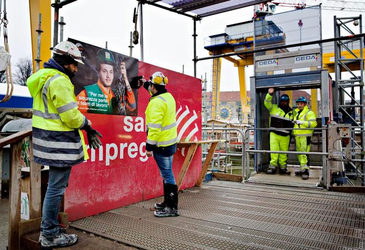Opråb. Metroarbejderne Milton Horais og Andrea Piccaia hænger plakater op på byggepladsen ved Nørrebroparken. Byggeriet er plaget af dårlig arbejdsmiljø, for mange ulykker og masser af bøder, og nu skal der gøres noget ved det, siger hovedentreprenøren, CMT. 
