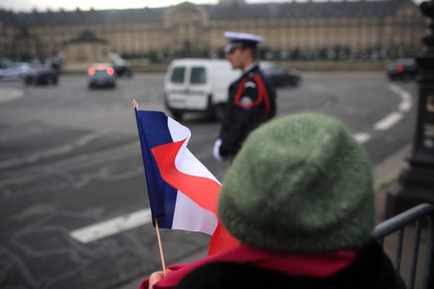 En kvinde er mødt op med det franske flag foran Les Invalides, hvor den officielle ceremoni for at markere massedrabene finder sted. 